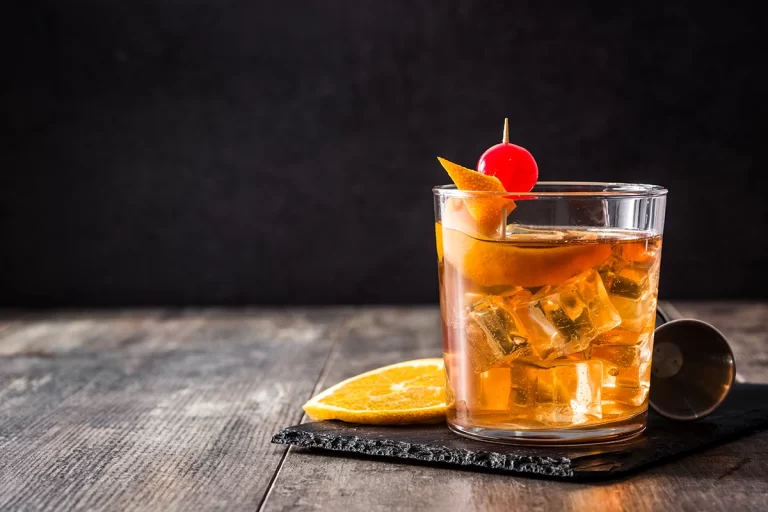 a glass of liquid with ice and orange slice on top