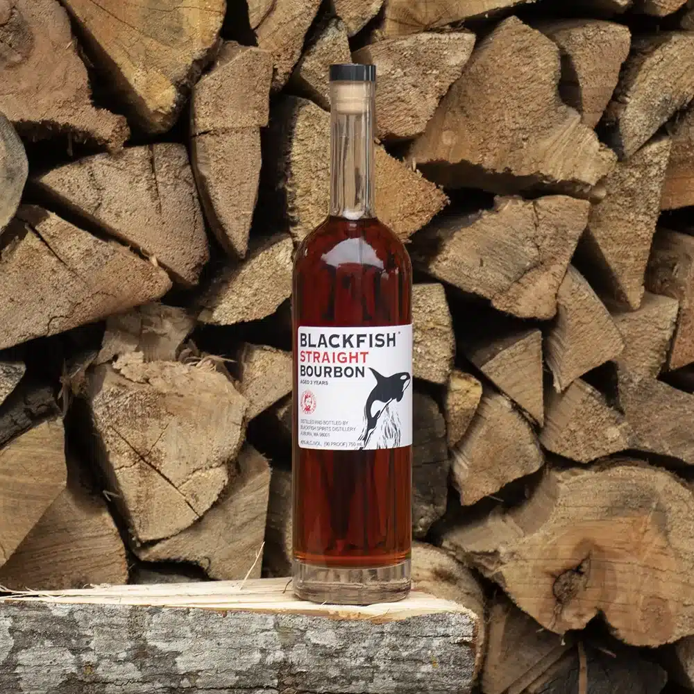 Bottle of Bourbon in front of a wood pile