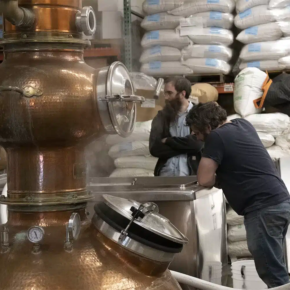 a group of men standing in front of a large copper tank